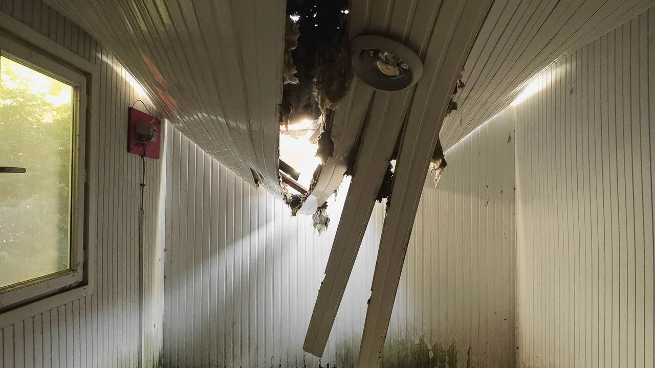 A ceiling torn open by water and fire damage inside a building.